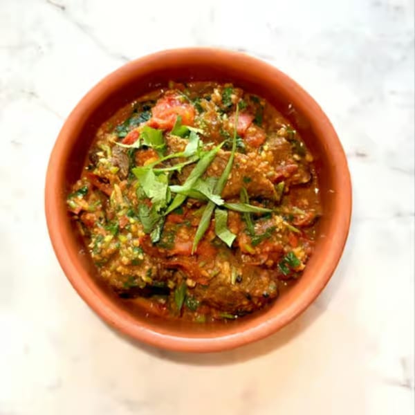 Himalayan Wild Yak's Nepalese curry with meat, tomatoes, and herbs in a rustic clay bowl.