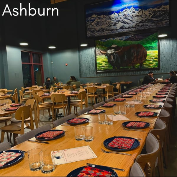 The Himalayan Wild Yak restaurant interior features a long communal table, smaller tables, and large yak and mountain murals.