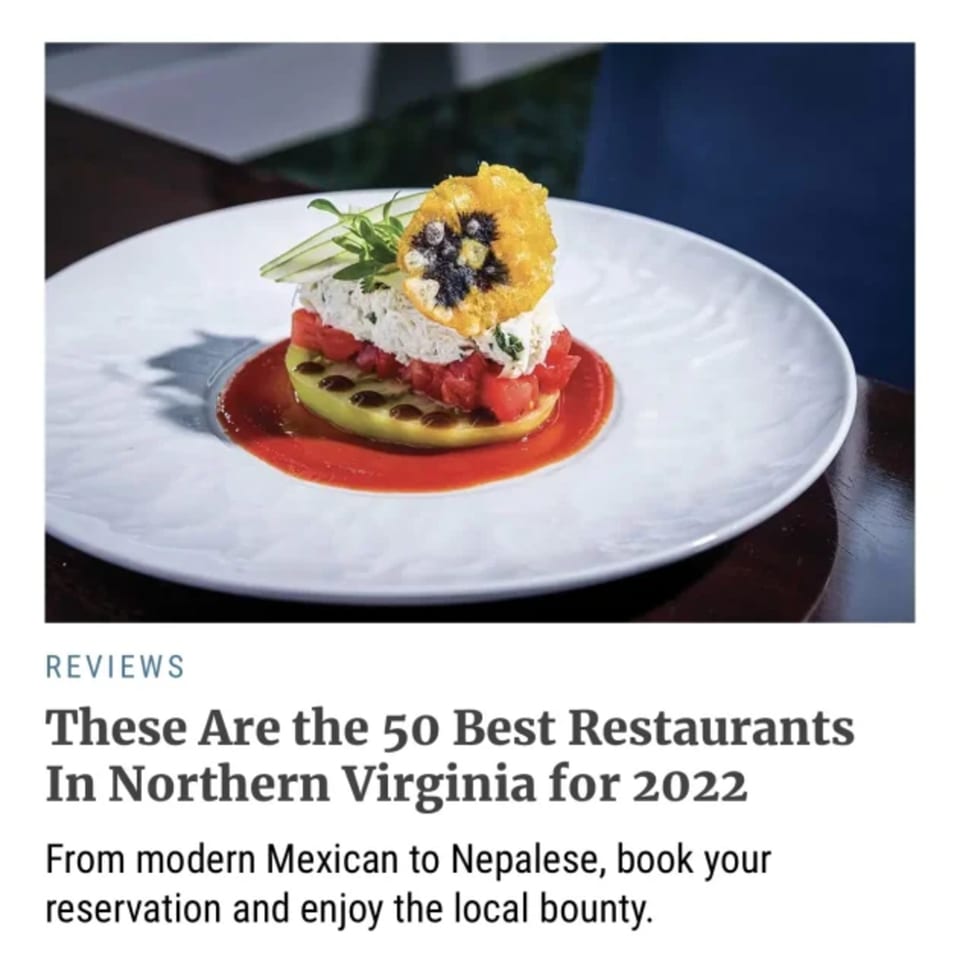 A Nepalese dish with white cheese, diced tomatoes, and a yellow edible flower on a white plate.
