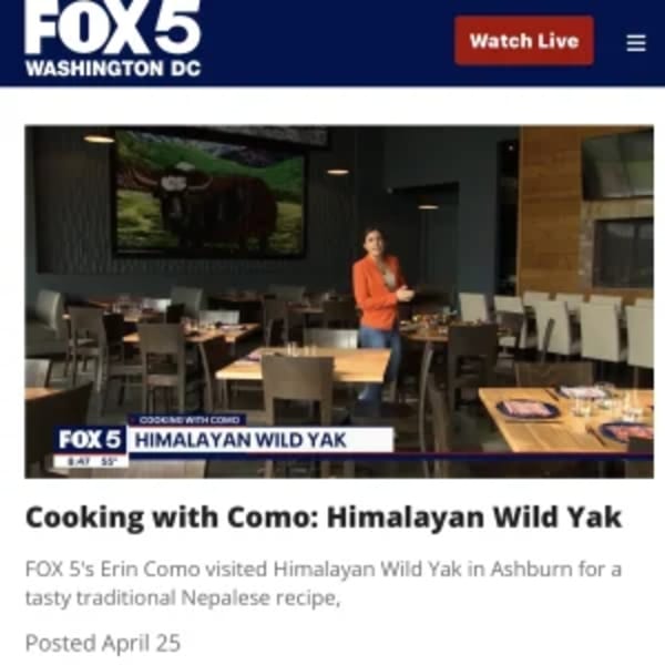 A woman in an orange shirt stands in the dining room of Himalayan Wild Yak restaurant.