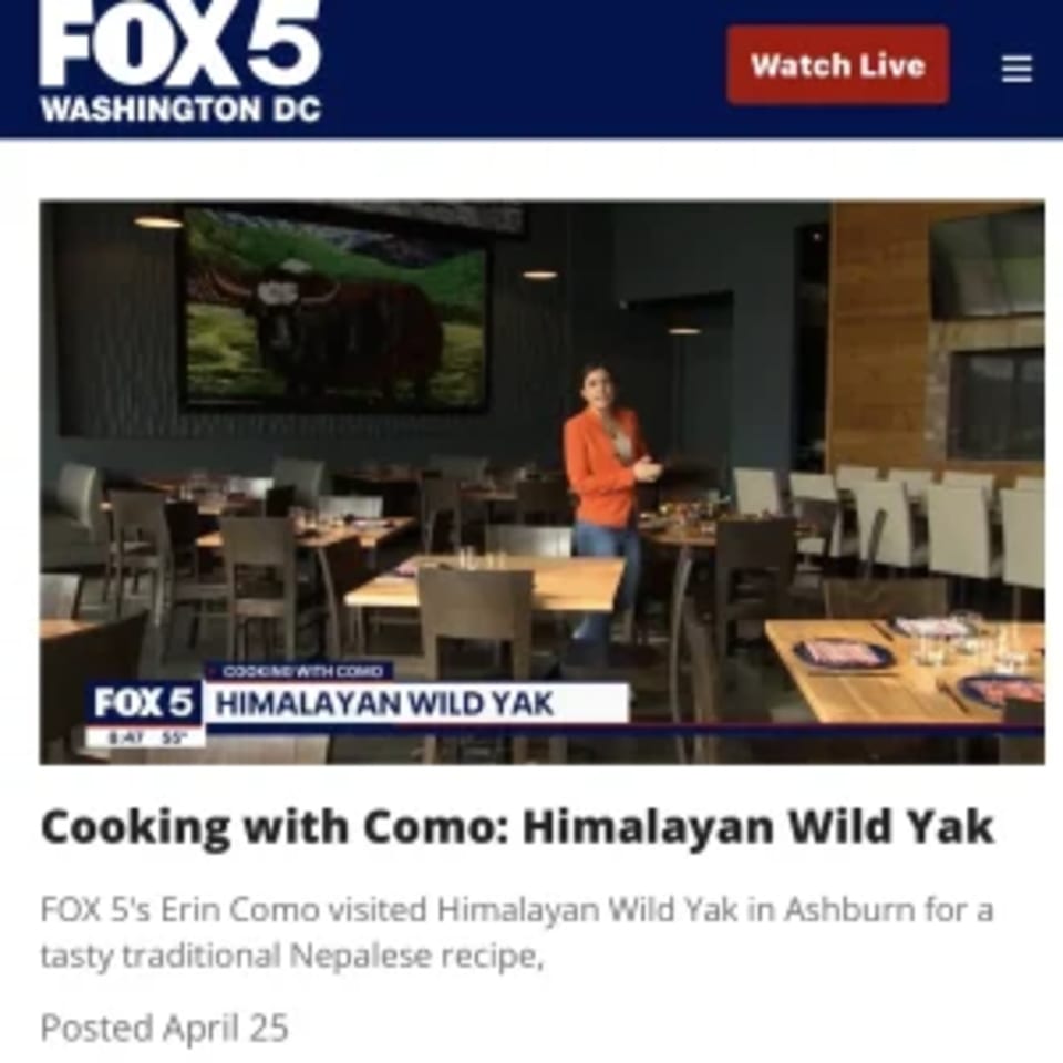 A woman in an orange shirt stands in the dining room of Himalayan Wild Yak restaurant.